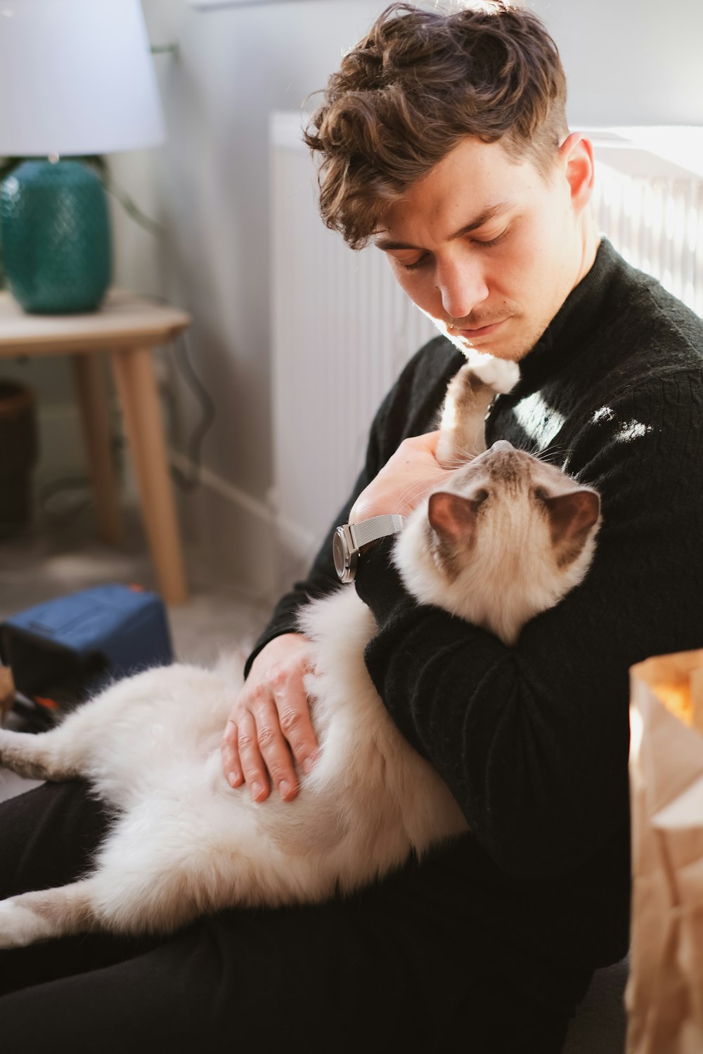 woman in black sweater holding white and brown cat