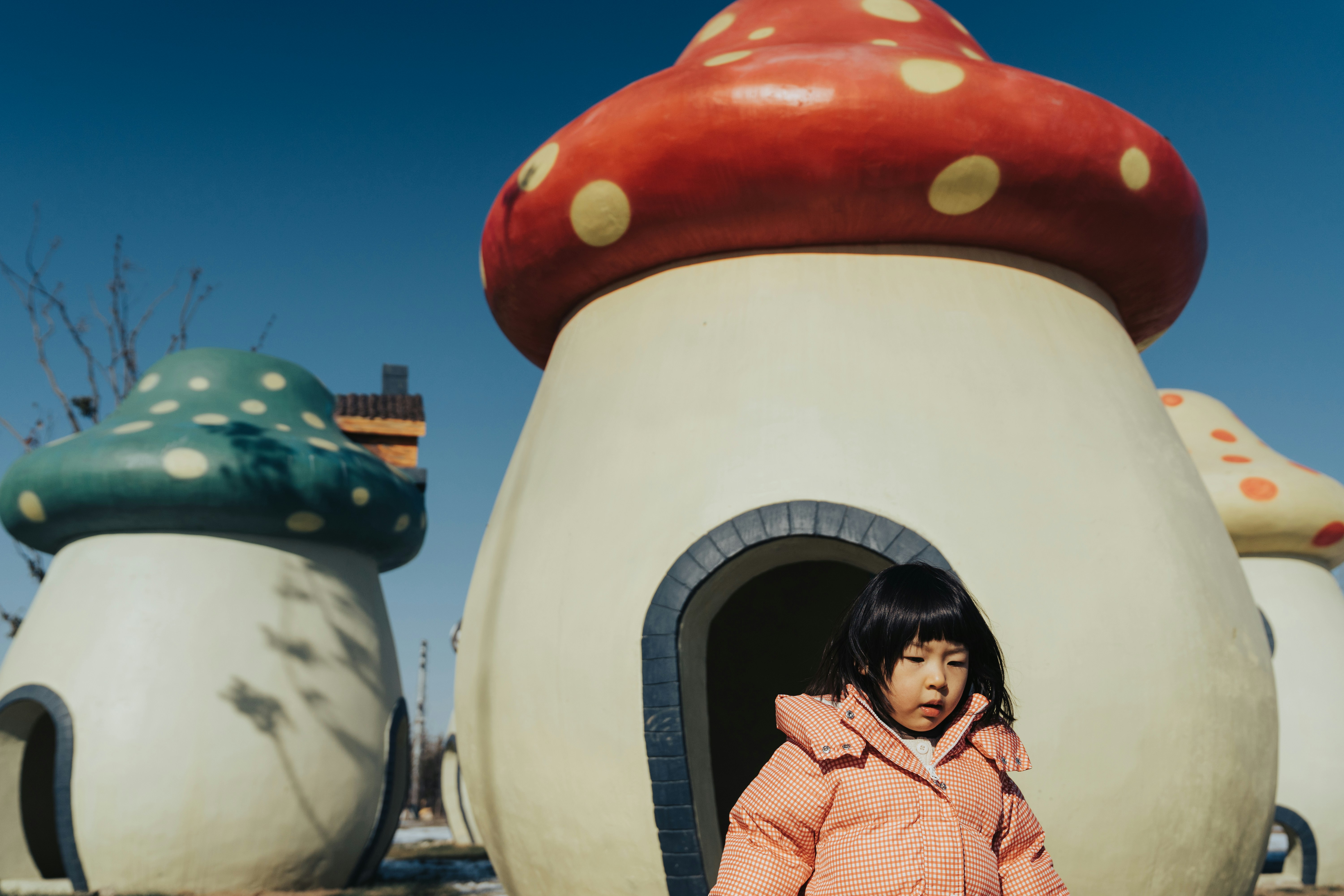 woman in pink jacket standing beside white and red concrete structure during daytime