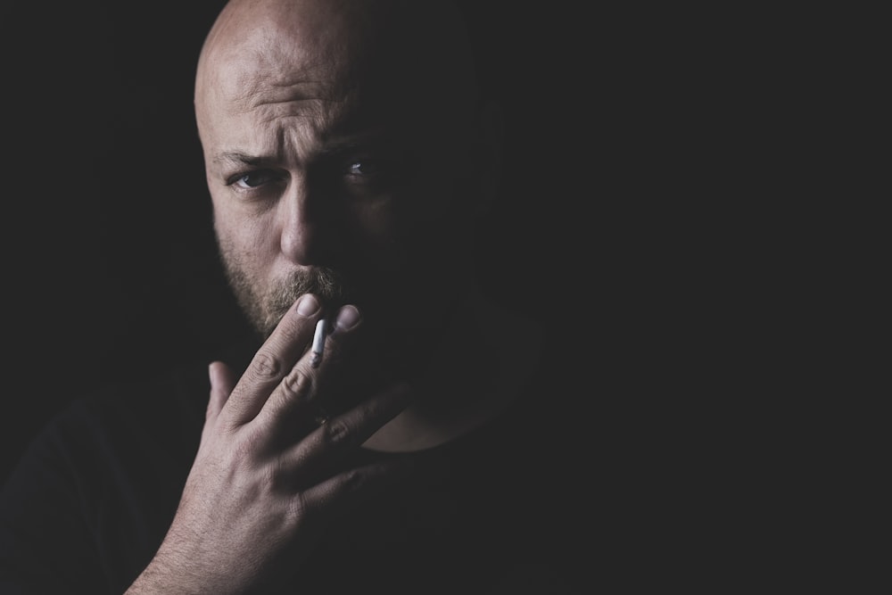 man in black tank top smoking cigarette