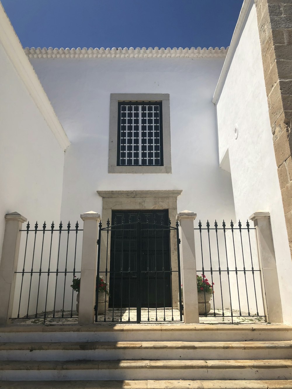 Puerta de metal negro sobre edificio de hormigón blanco