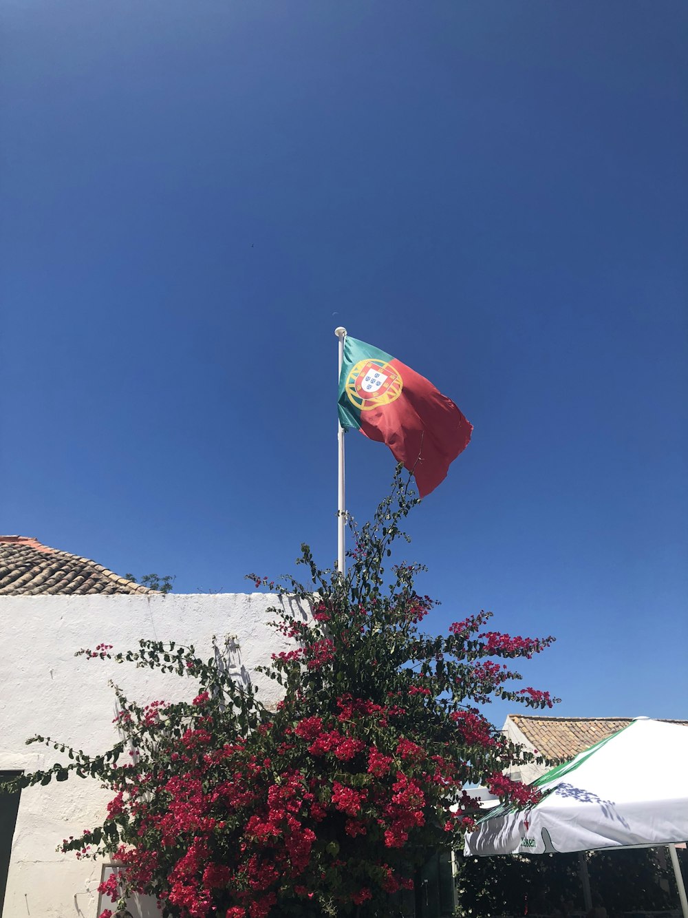 bandeira vermelha e branca na parede de concreto branca sob o céu azul durante o dia