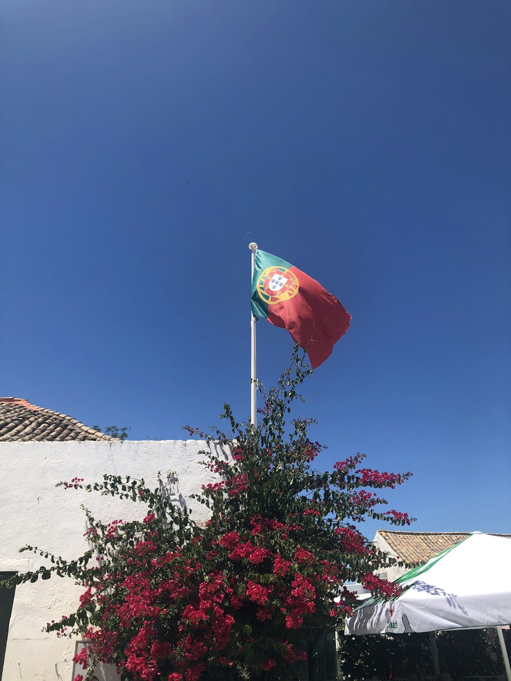 drapeau rouge et blanc sur mur de béton blanc sous ciel bleu pendant la journée