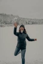 woman in black jacket and blue denim jeans standing on snow covered ground during daytime