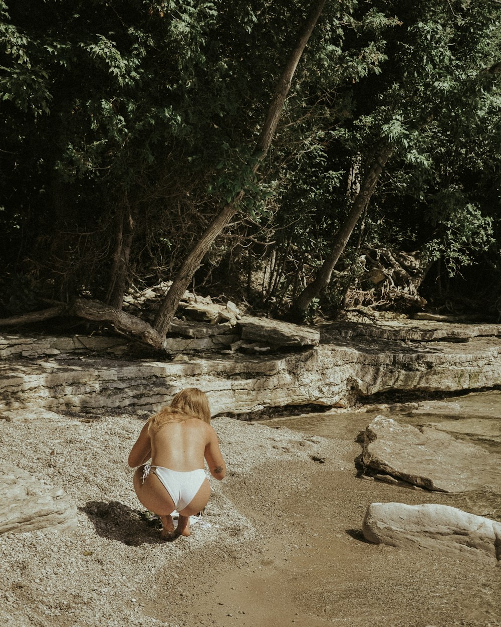 woman in white bikini sitting on brown sand during daytime