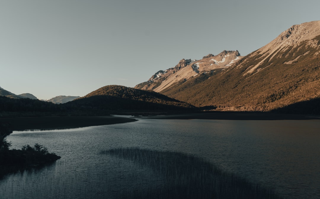 brown and white mountains beside body of water during daytime