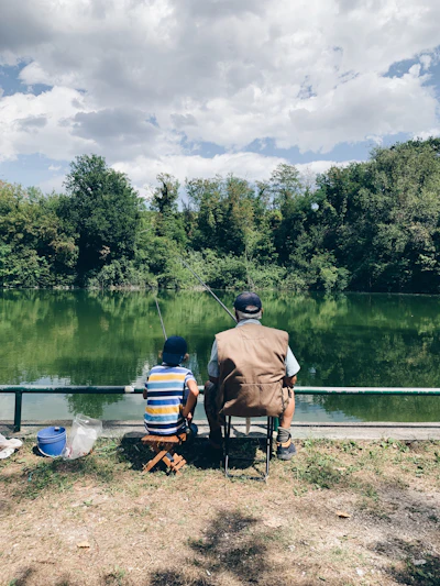 Person fishing calmly from a lake bank during the day