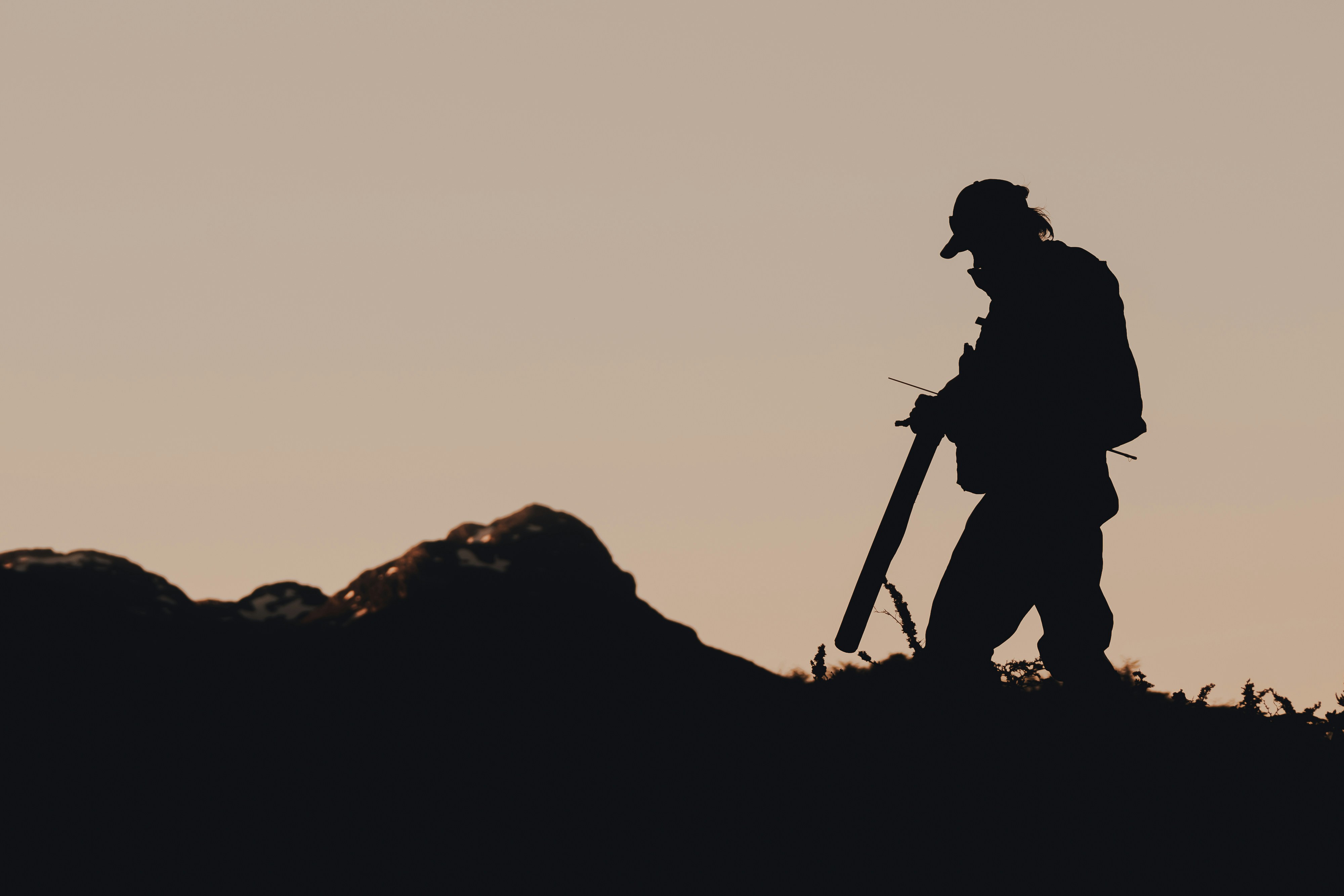 silhouette of man holding a stick on a rock