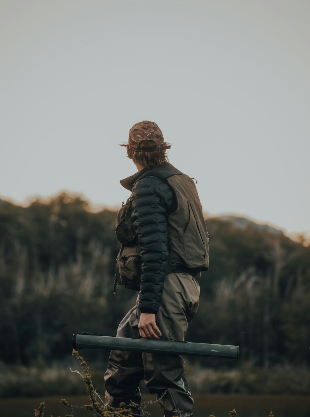 man in black leather jacket and brown backpack standing on blue metal railings during daytime