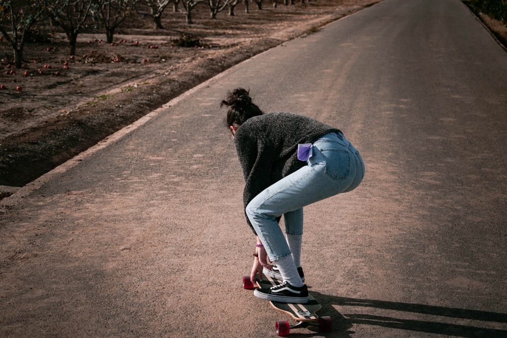 woman in black long sleeve shirt and blue denim jeans running on road during daytime