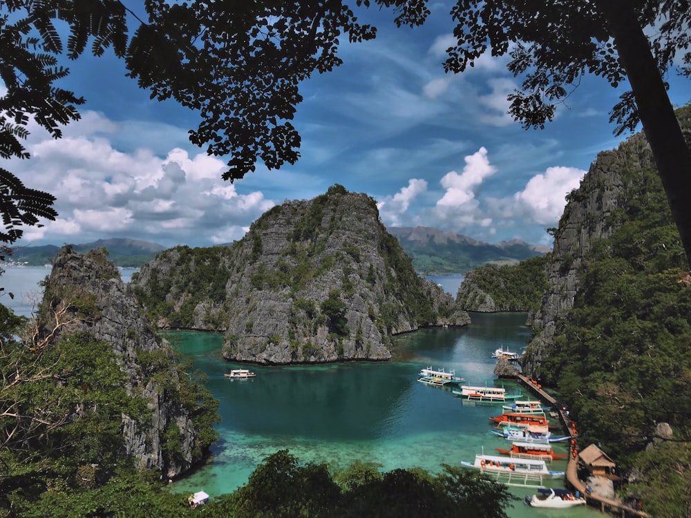 green lake surrounded by green trees and mountain under blue and white cloudy sky during daytime