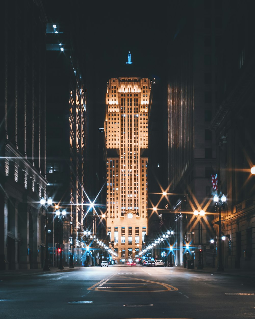 夜間の高層ビル間の道路を走る車
