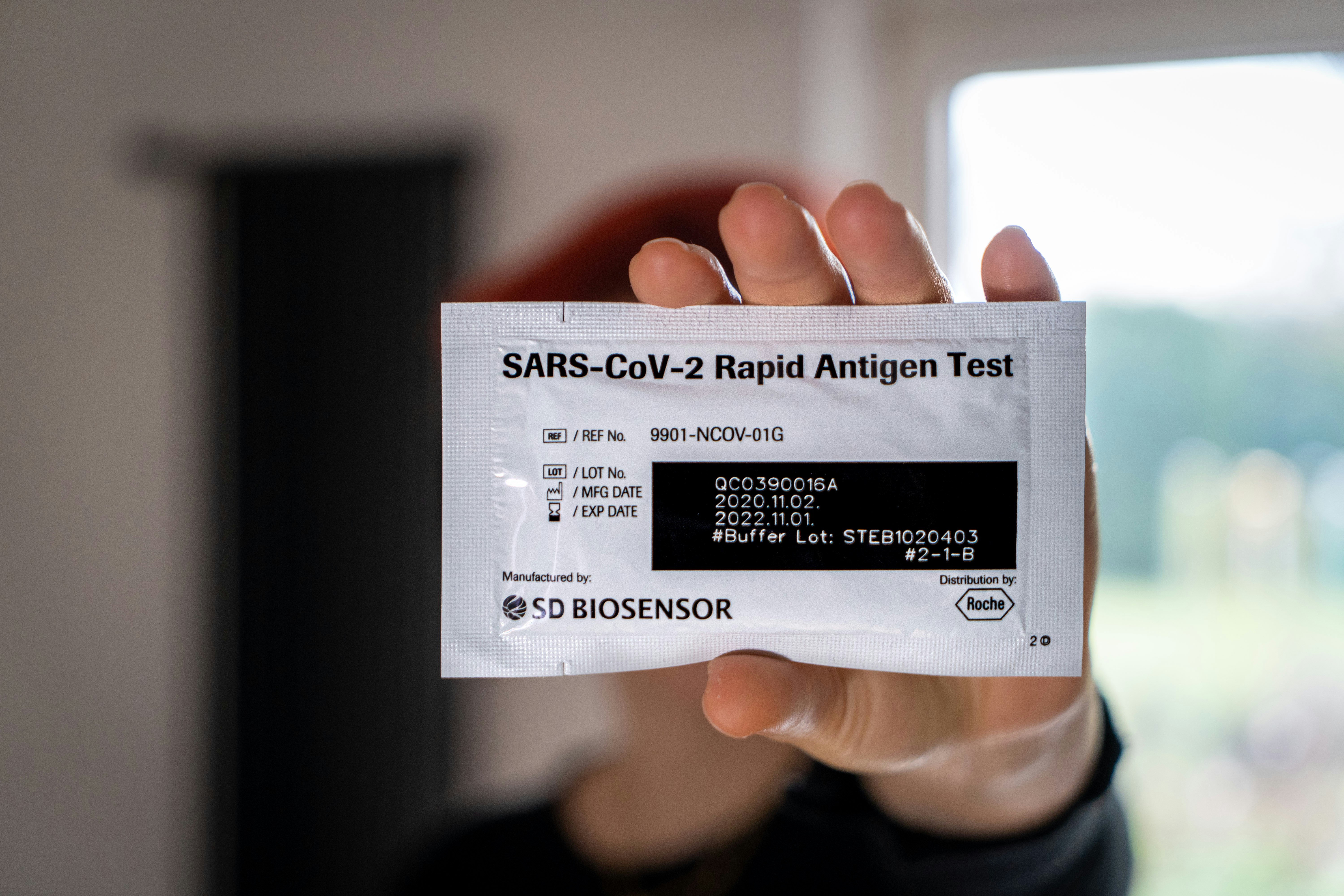 A woman holding up a Covid Antigen Test, as used in Germany.