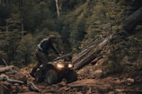 Smiling rider in North Carolina blue gear navigating a rocky ATV trail with vibrant fall foliage.