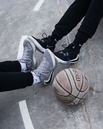 person in black pants and white nike basketball shoes