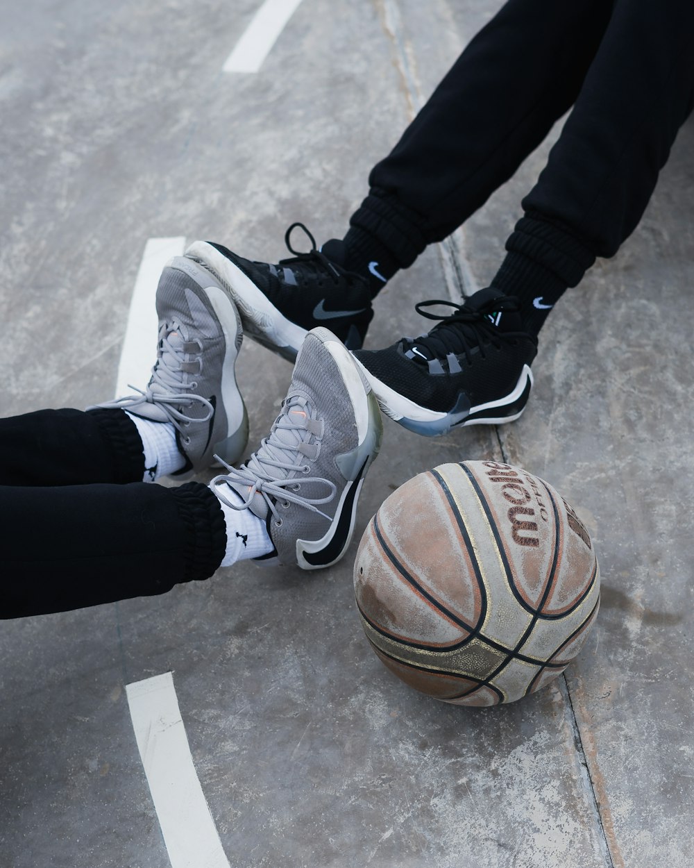 person in black pants and white nike basketball shoes