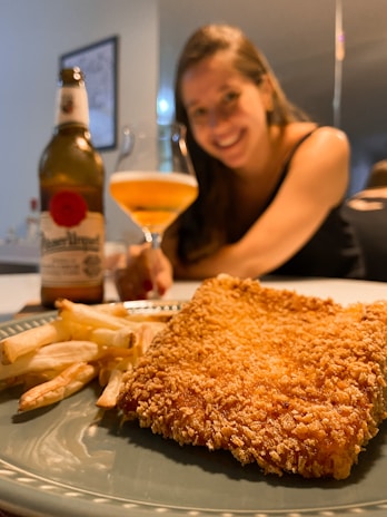 Refreshing craft beer poured into a frosty glass beside a plate of sweet chili chicken tenders.
