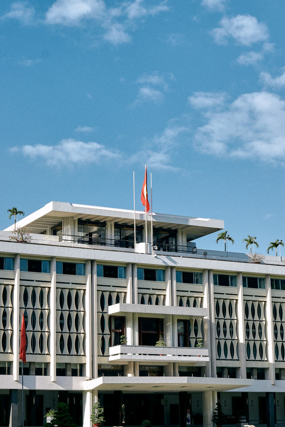 white concrete building with flags on top under blue sky during daytime