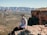 man in white dress shirt and black pants sitting on brown rock during daytime