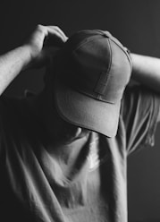 grayscale photo of person holding cap