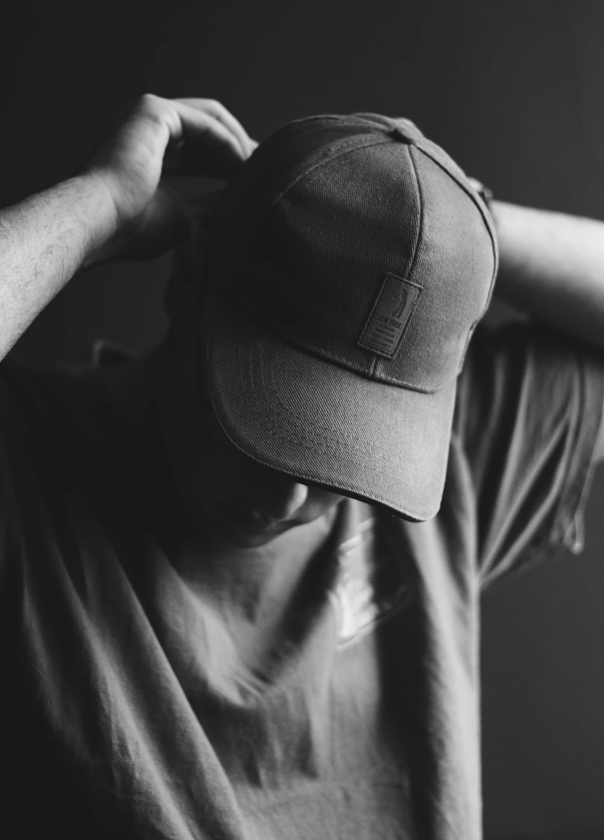 Grayscale photo of a person holding a cap