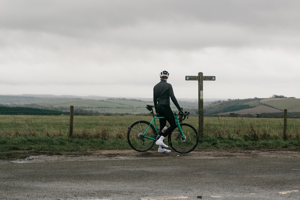 man in black jacket riding on green mountain bike on road during daytime