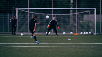 2 men playing soccer on green field during daytime