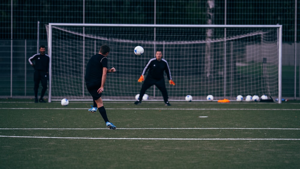 2 men playing soccer on green field during daytime