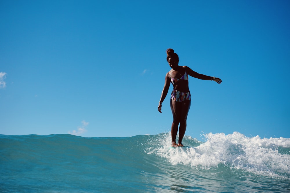 woman in black bikini standing on water during daytime