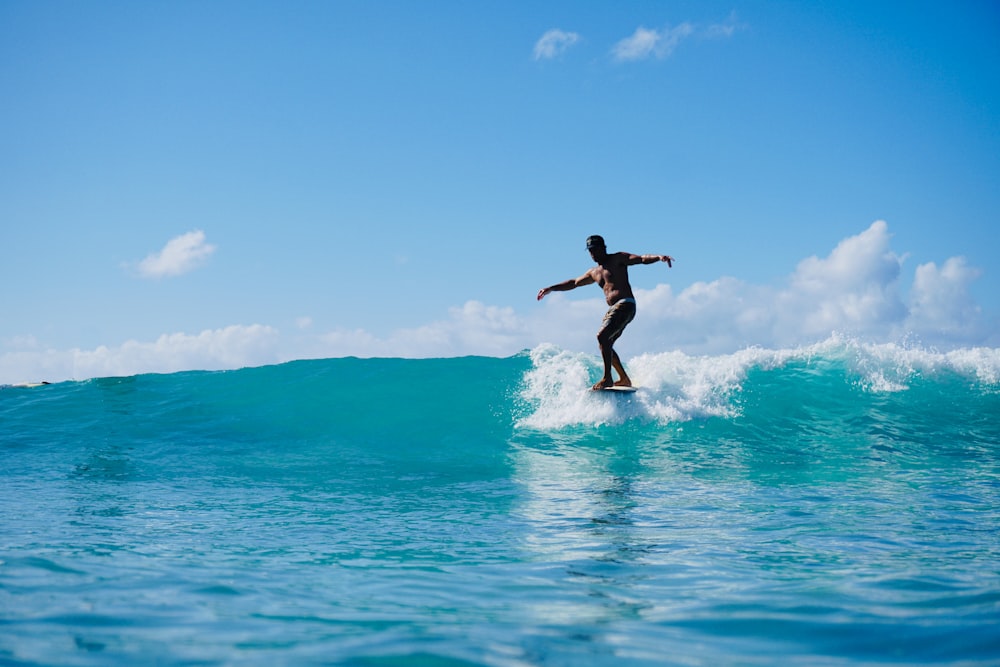 man in black shorts surfing on blue sea during daytime