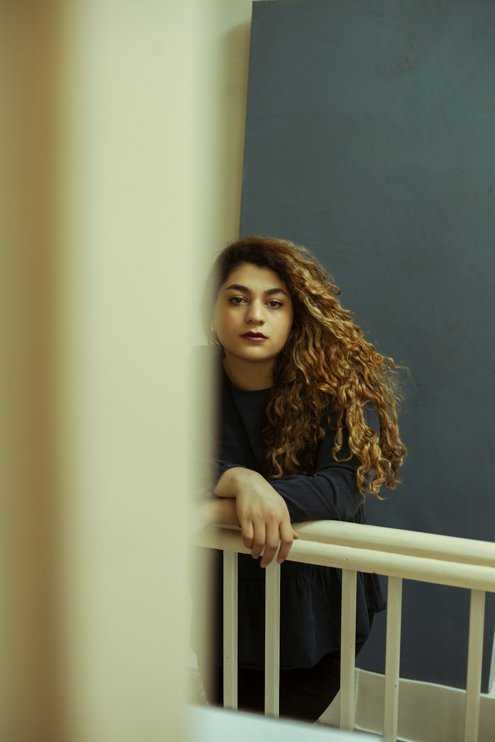 woman in black shirt leaning on white wooden fence