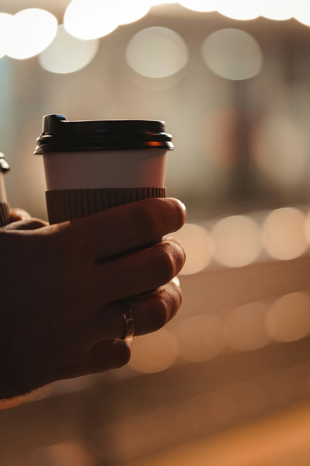 person holding brown and black disposable cup