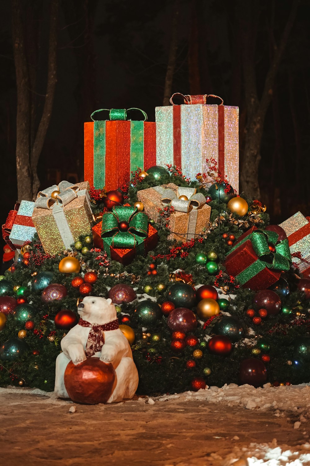 Contenitore di regalo rosso e bianco accanto all'albero di Natale verde con palline e palline