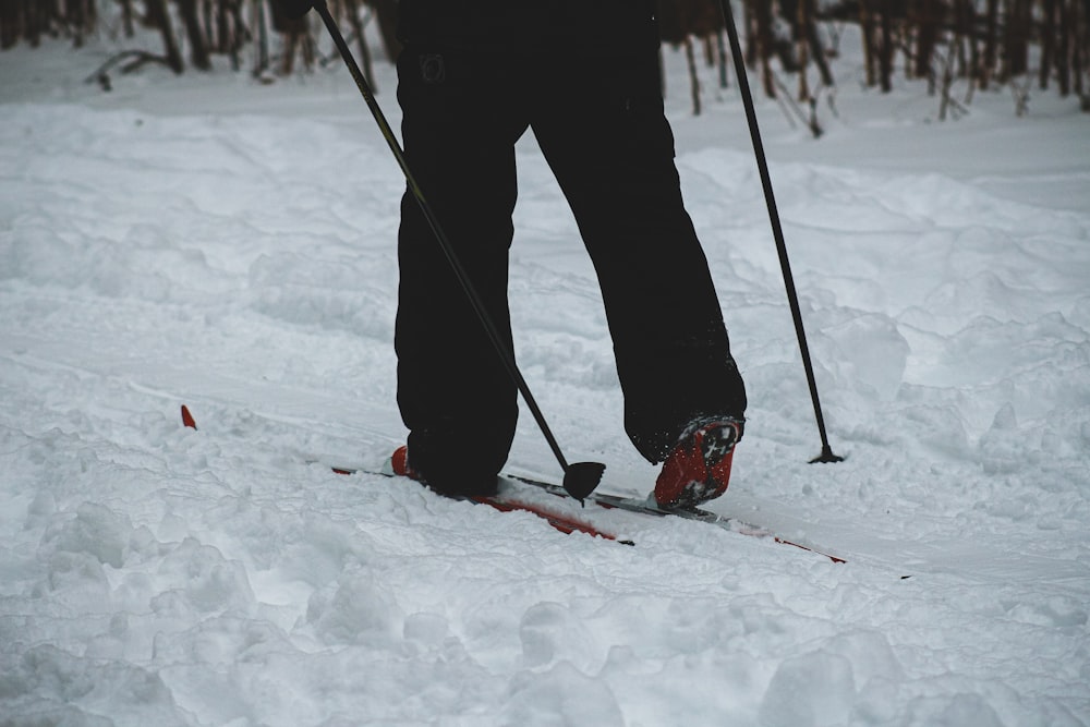 person in black pants and red snow ski