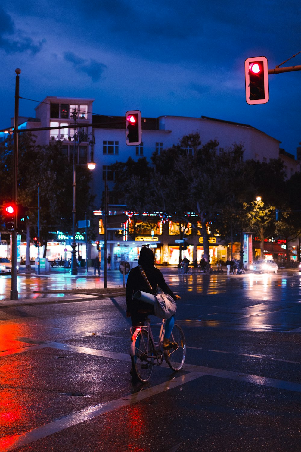 Mann in schwarzer Jacke fährt nachts Fahrrad auf der Straße