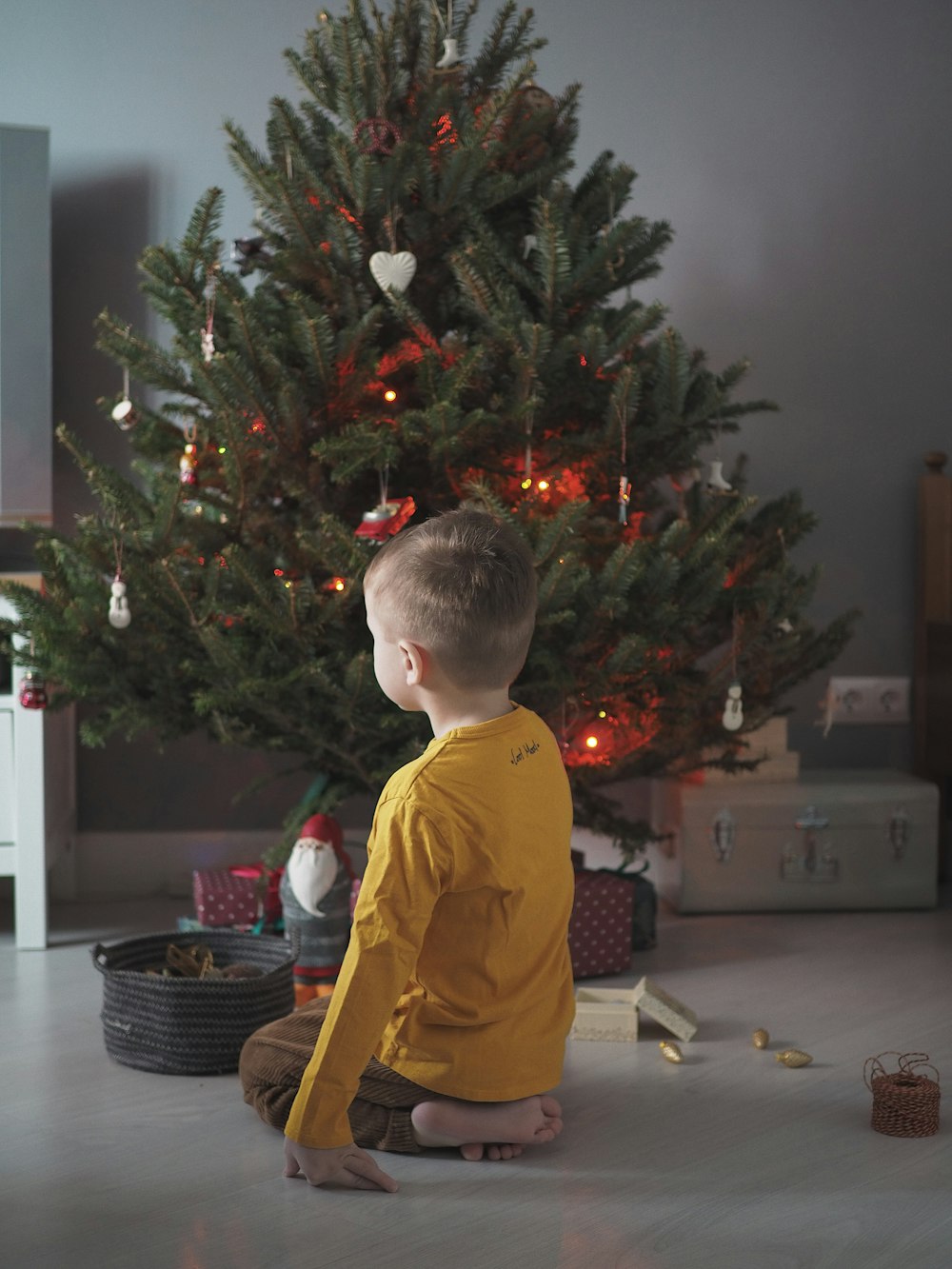 boy in yellow polo shirt standing beside christmas tree