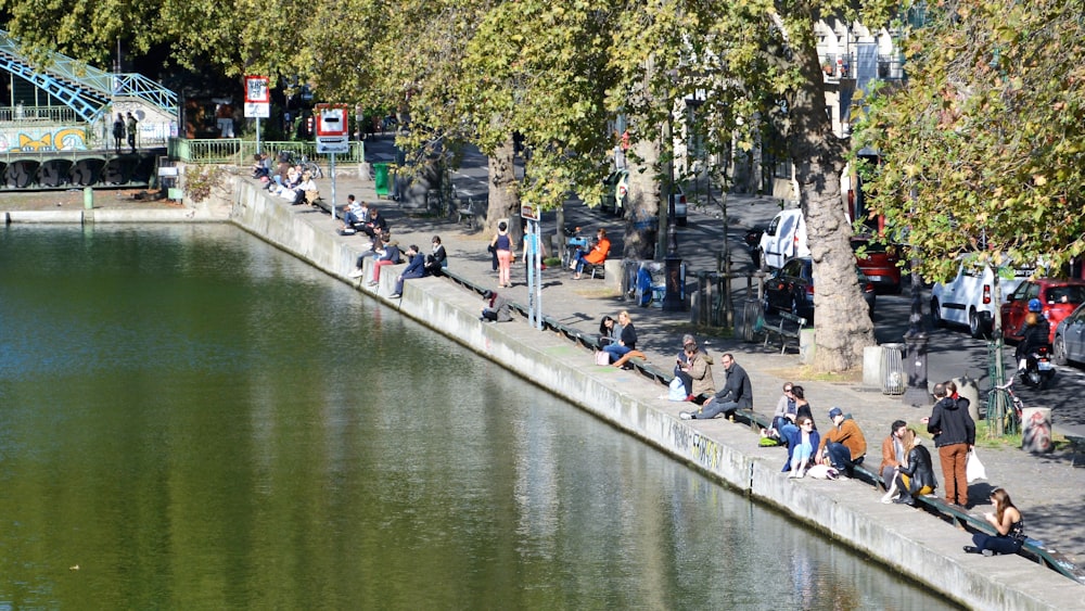 Menschen, die tagsüber auf dem Bürgersteig in der Nähe des Flusses spazieren gehen