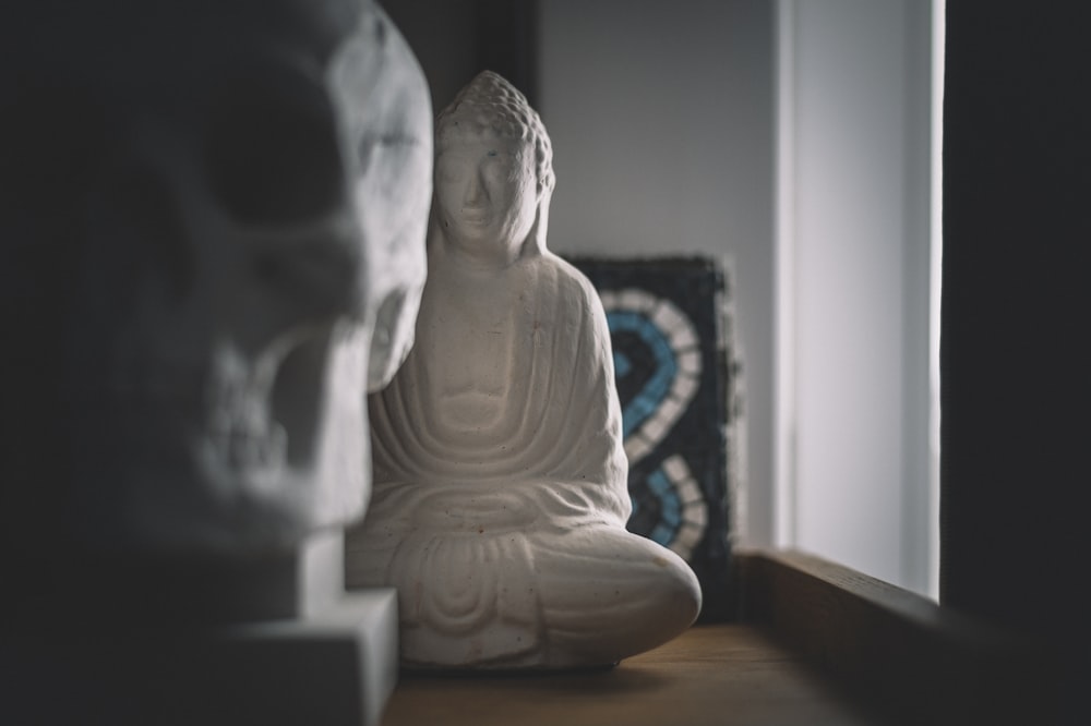 weiße Keramik-Buddha-Figur auf braunem Holztisch