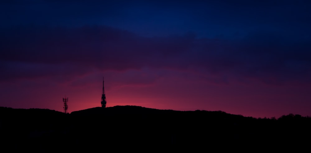 silhouette of person standing on hill during sunset