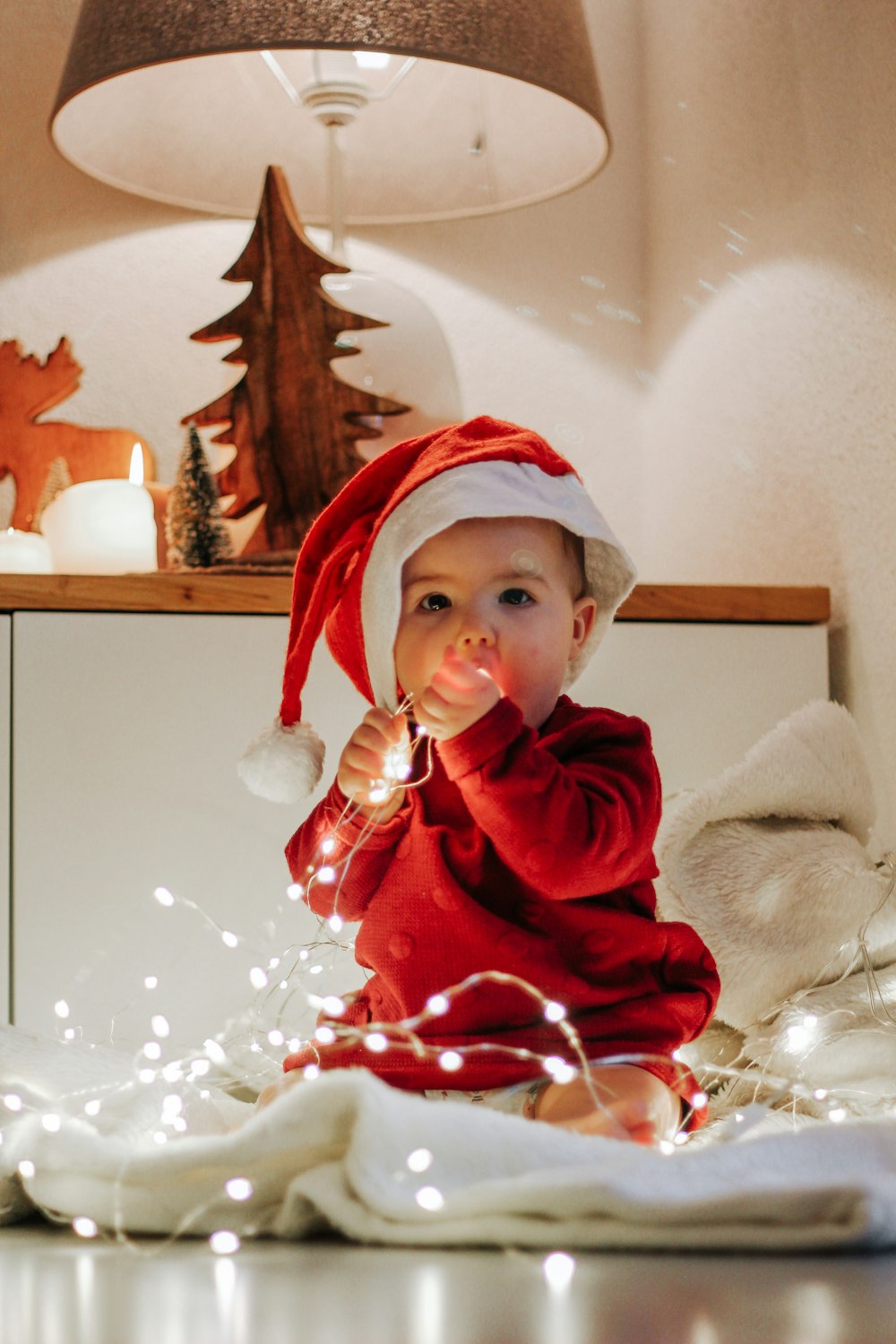 child in red hoodie holding white and red lollipop