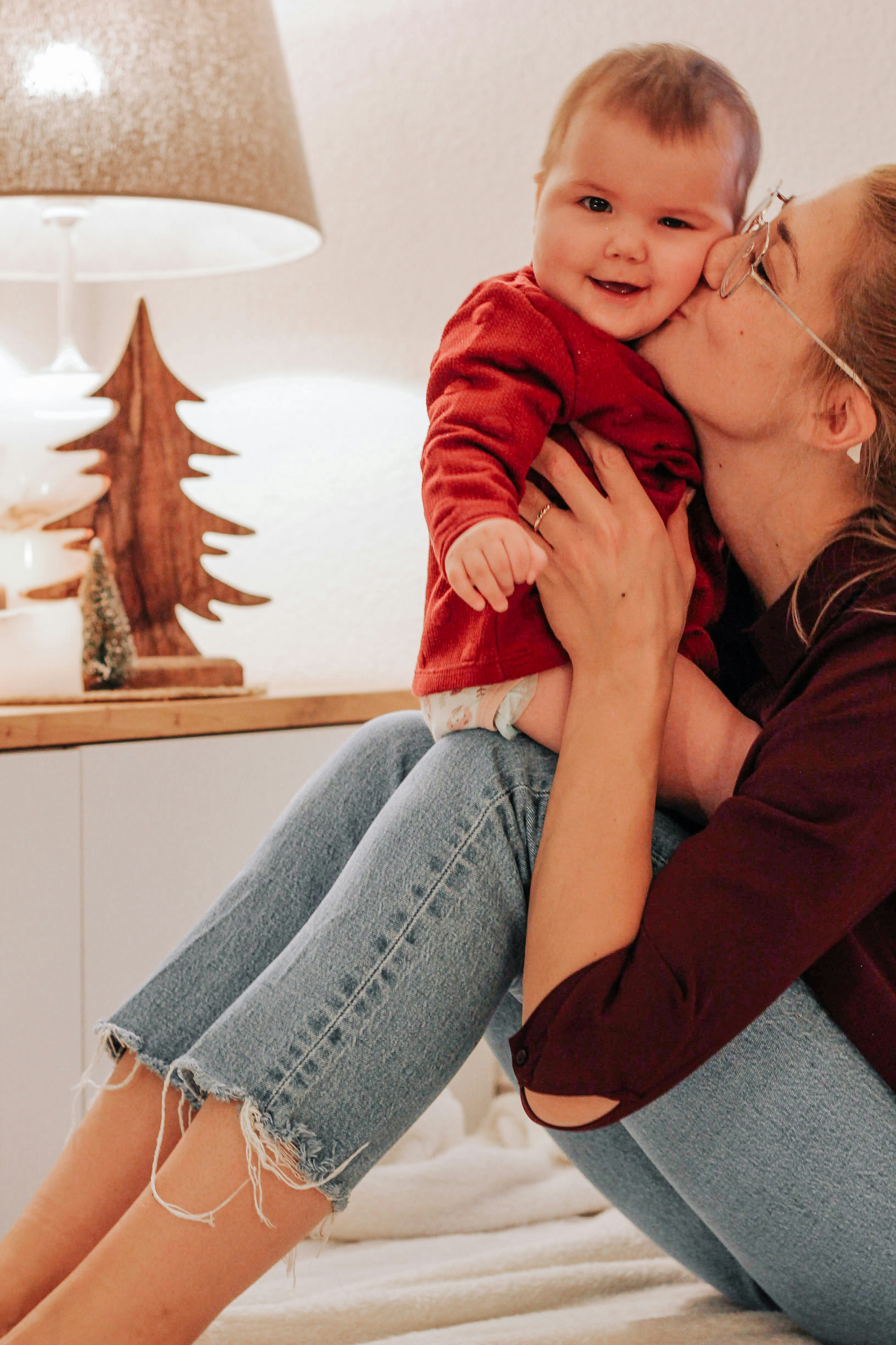 woman in red jacket and blue denim jeans sitting on brown wooden chair