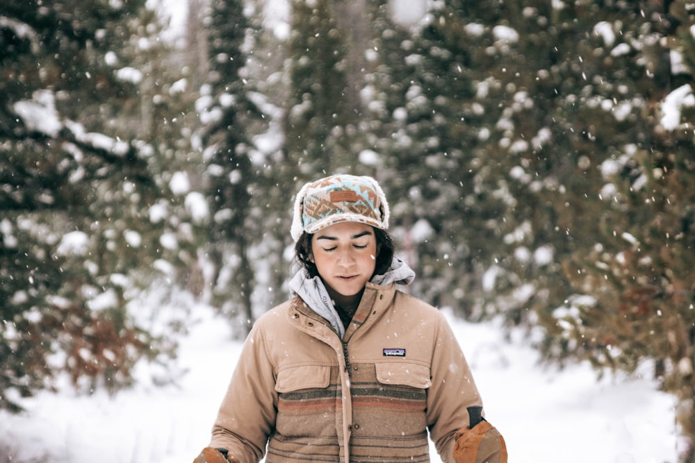 woman in brown jacket standing on snow covered ground during daytime