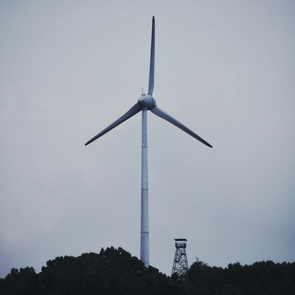 white wind turbine under gray sky