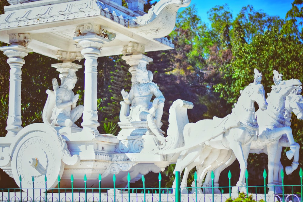 white concrete statue near green trees during daytime