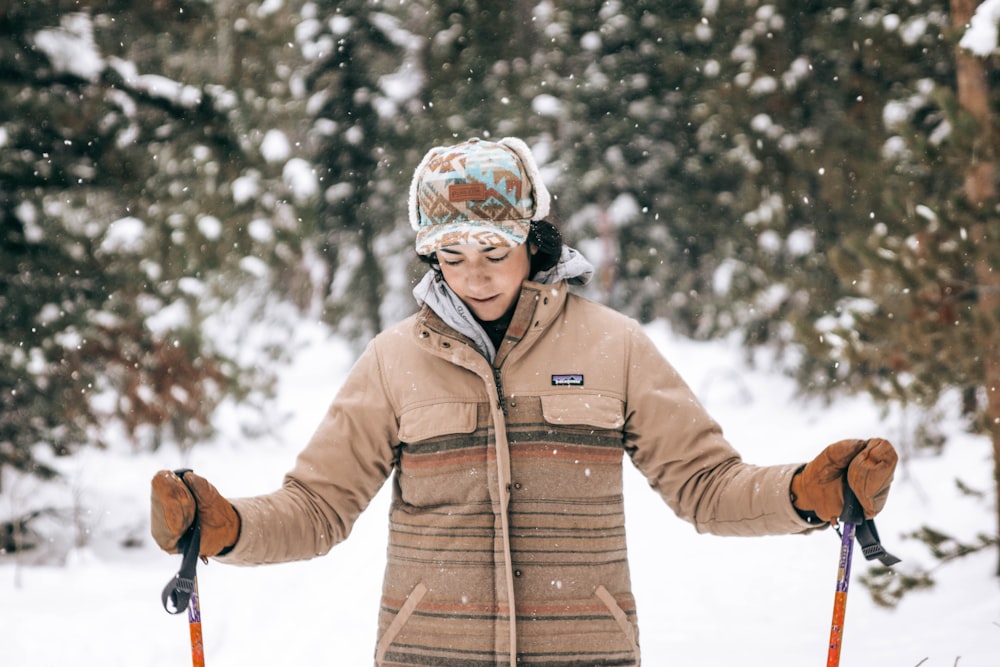 man in brown jacket and helmet standing on snow covered ground during daytime