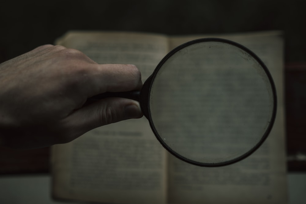 person holding magnifying glass with black frame