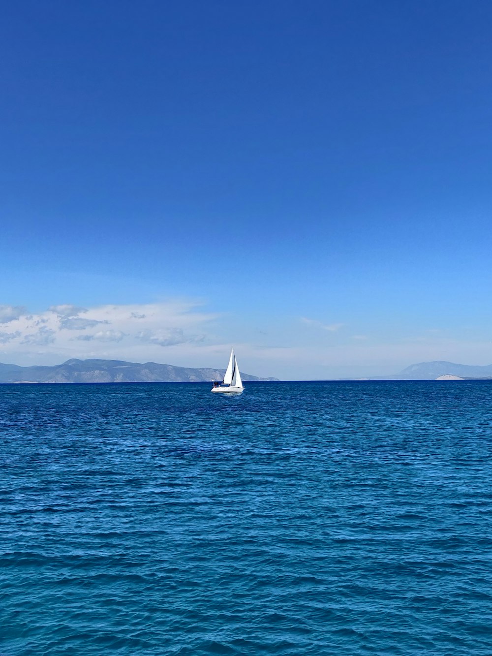 white sailboat on sea under blue sky during daytime