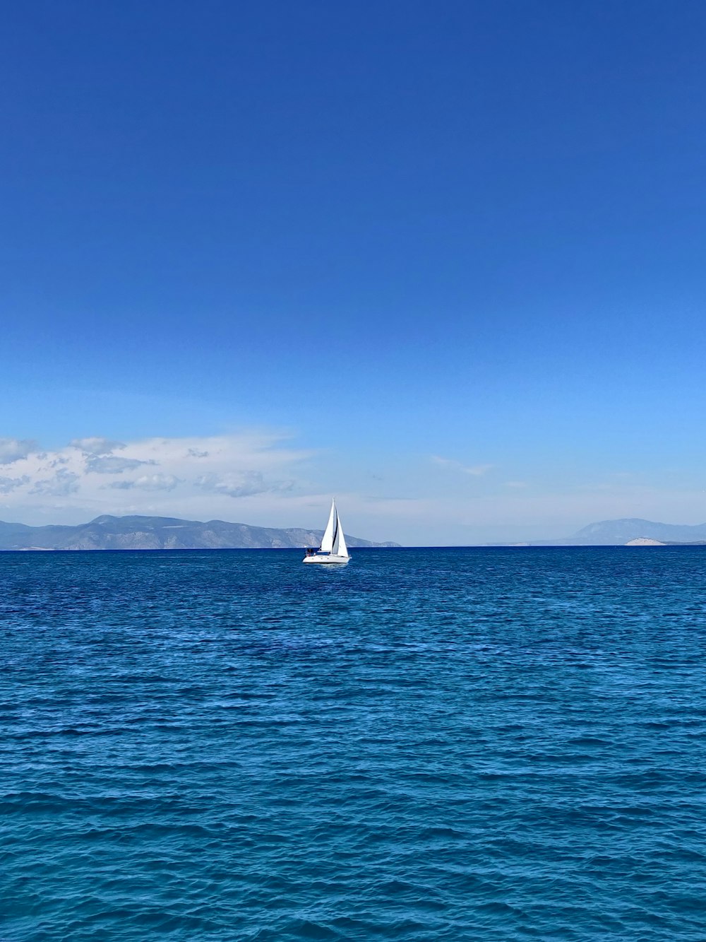 weißes Segelboot auf See unter blauem Himmel tagsüber