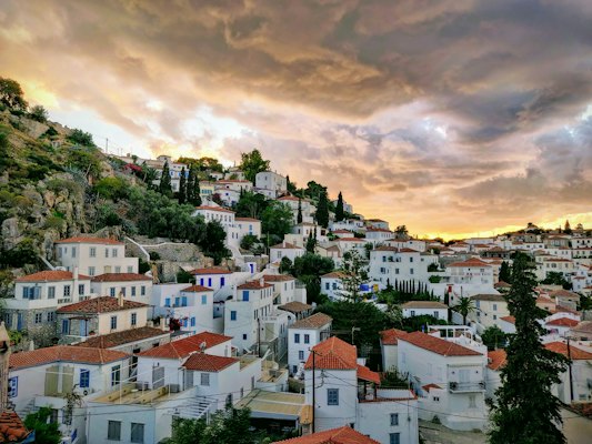 White and brown concrete houses under cloudy sky during daytime — Hydra, Greece