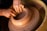 Hands skillfully shaping a clay pot on a spinning pottery wheel, the clay is wet and malleable under the fingers. The scene captures the intricate art of pottery making.