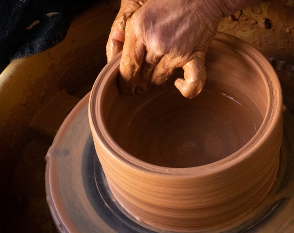 person holding round clay pot
